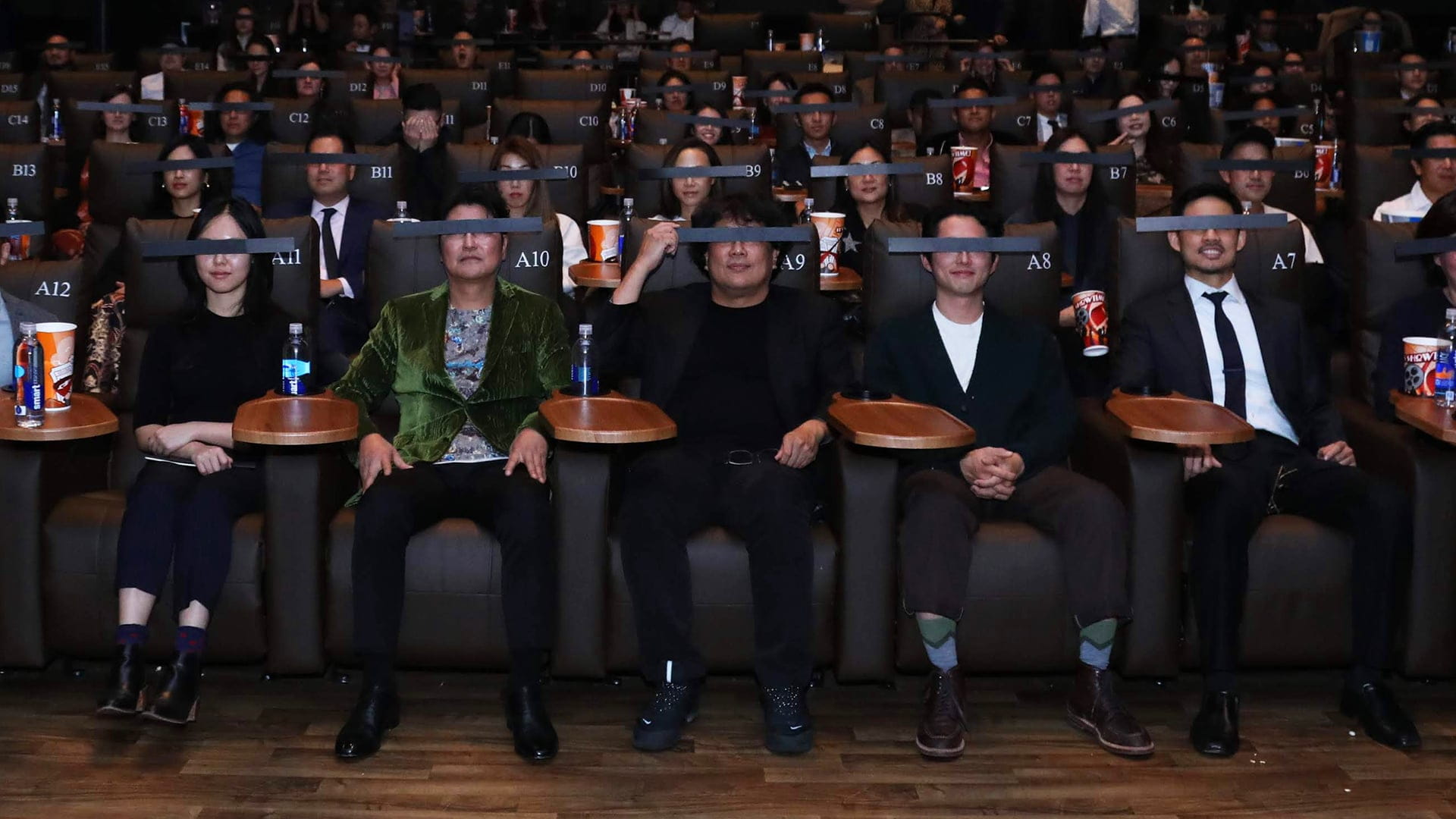 People sitting in the movie theatre wearing eye masks from Parasite screening.